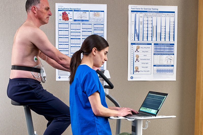 Patient auf dem Ergometer, Ärztin verfolgt das Belastungs-EKG