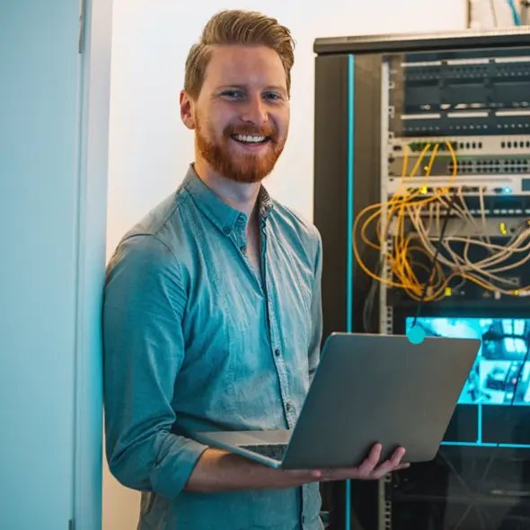 IT-Spezialist mit Laptop vor einem Serverschrank