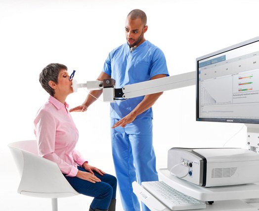 Patientin bei der Spirometrie mit MicroGard IIB, der Anwender steht daneben